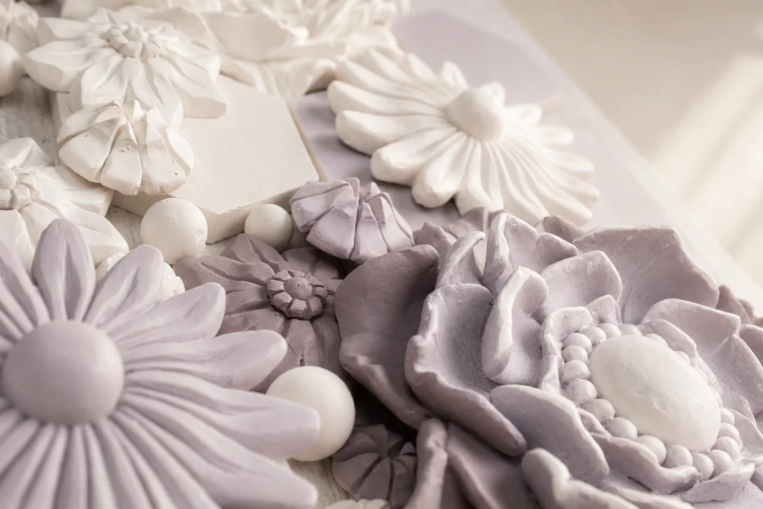 Handcrafted floral bas-relief detail in soft ivory and muted violet tones by AnaKleo Studio